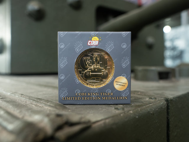 A gold medallion coin showcasing an outline of the King Tiger V2 Tank. The Medallion is in a grey box with the COBI & The Tank Museum Logo