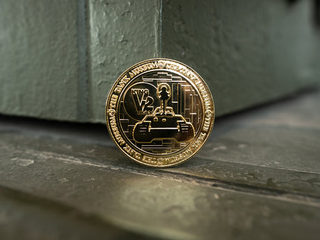 A gold-colored commemorative medallion, showcasing a design of the King Tiger V2 tank with The Tank Museum logo on the edges